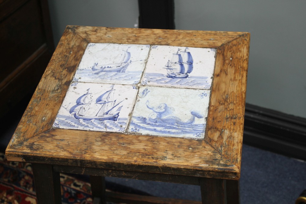 An early 20th century square pine occasional table, inset four Delft tiles, top 38cm sq., H.64cm